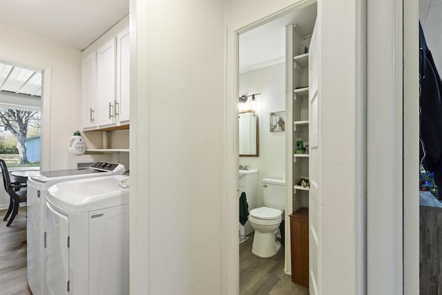 washroom featuring cabinets, wood-type flooring, and separate washer and dryer