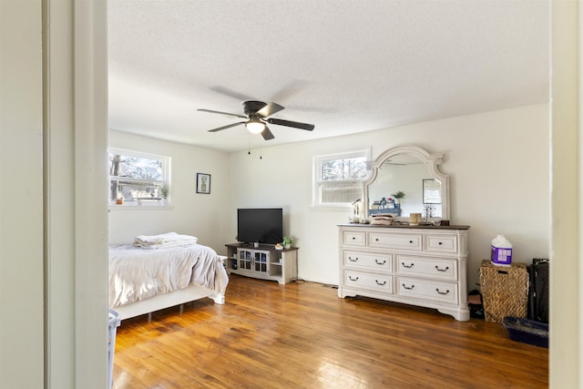 bedroom featuring multiple windows, hardwood / wood-style flooring, a textured ceiling, and ceiling fan