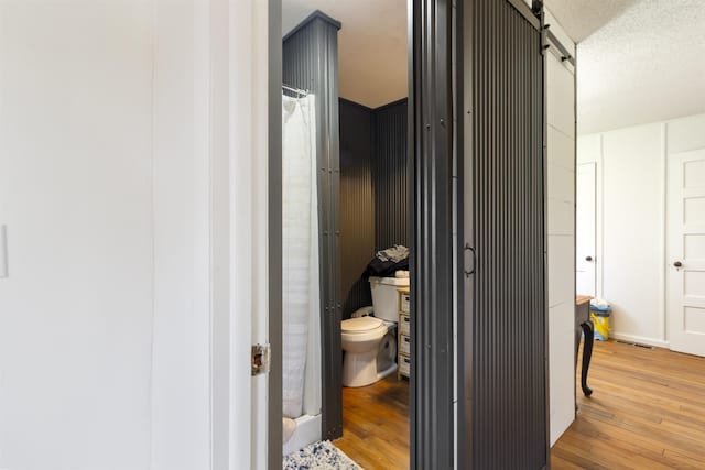 bathroom with hardwood / wood-style flooring, a textured ceiling, and toilet