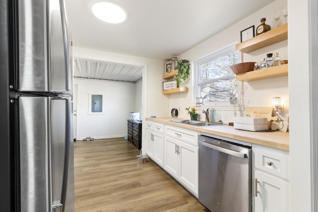 kitchen featuring white cabinetry, stainless steel appliances, electric panel, light hardwood / wood-style floors, and sink