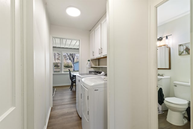 washroom featuring cabinets, washing machine and dryer, and light hardwood / wood-style floors