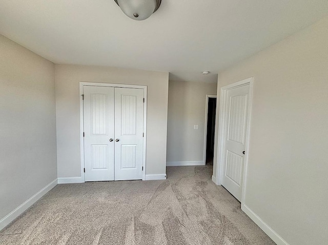 unfurnished bedroom featuring a closet and light colored carpet