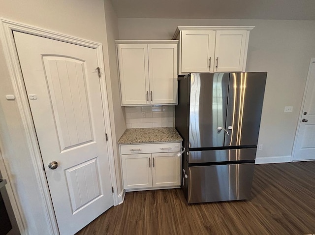 kitchen featuring light stone counters, stainless steel fridge, decorative backsplash, dark hardwood / wood-style flooring, and white cabinets