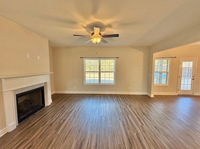 unfurnished living room with a tile fireplace, ceiling fan, and dark hardwood / wood-style flooring