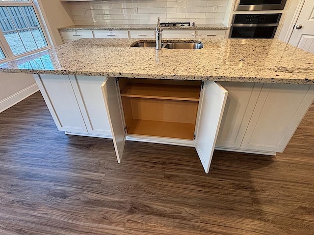 kitchen featuring dark hardwood / wood-style flooring, white cabinetry, a kitchen island with sink, and wall oven