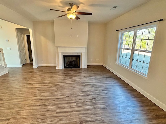 unfurnished living room featuring hardwood / wood-style floors, a tile fireplace, and ceiling fan