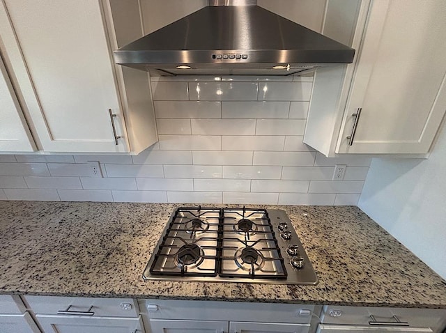 kitchen featuring white cabinetry, stone counters, tasteful backsplash, stainless steel gas stovetop, and range hood