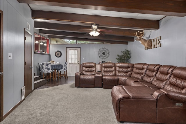  - carpeted living room with beamed ceiling, a ceiling fan, and wooden walls