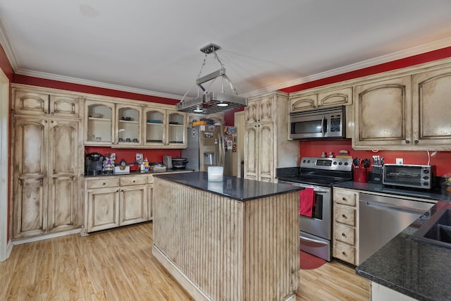  - kitchen with appliances with stainless steel finishes, dark countertops, ornamental molding, light wood-style flooring, and a kitchen island