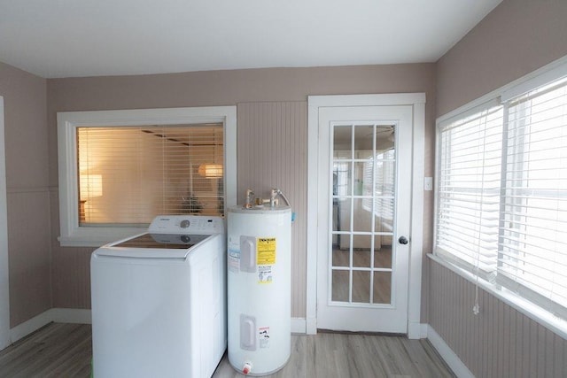 laundry area with light hardwood / wood-style floors, washer / dryer, electric water heater, and a wealth of natural light