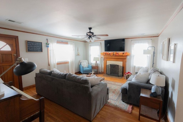 living room featuring ceiling fan, wood-type flooring, and crown molding