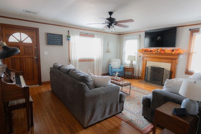 living room featuring ornamental molding, ceiling fan, dark wood-type flooring, and a tiled fireplace