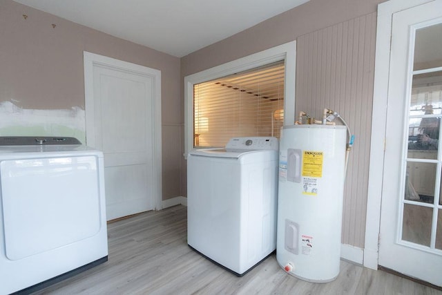 clothes washing area with light wood-type flooring, electric water heater, and washing machine and dryer