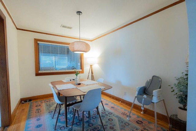 dining room with hardwood / wood-style floors and crown molding