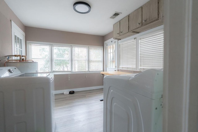 laundry area with washing machine and dryer, water heater, and light wood-type flooring