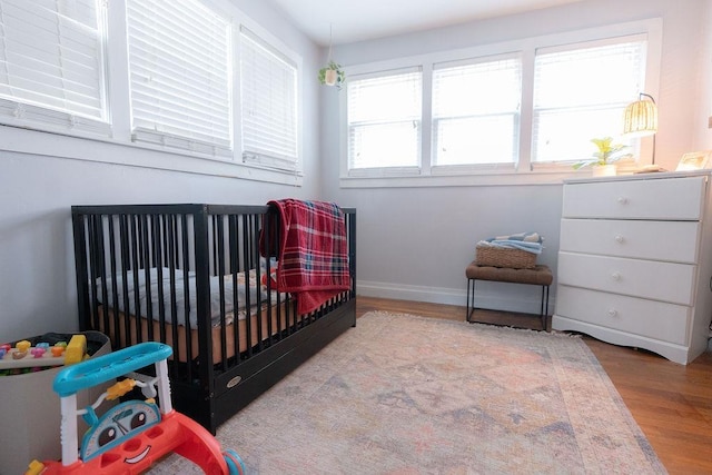 bedroom with light hardwood / wood-style floors and a nursery area