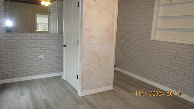 bathroom featuring hardwood / wood-style floors, ceiling fan, and brick wall