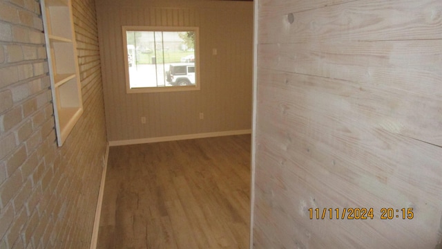 unfurnished room with hardwood / wood-style flooring and wooden walls