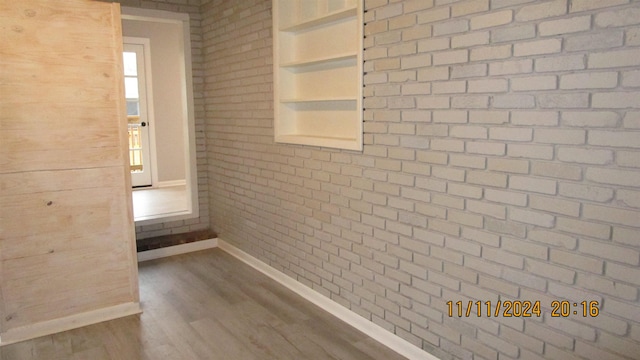 hallway with hardwood / wood-style floors and brick wall