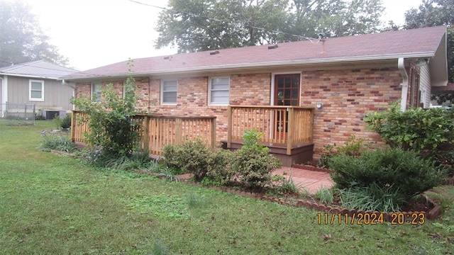 rear view of house featuring a lawn and a deck