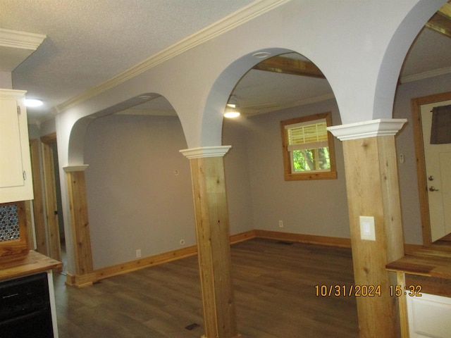 unfurnished living room featuring a textured ceiling, ornate columns, crown molding, and dark wood-type flooring