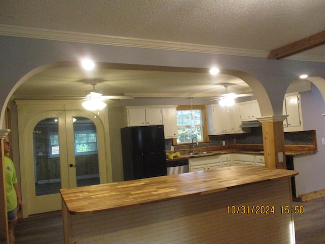 kitchen with tasteful backsplash, black refrigerator, white cabinets, and sink