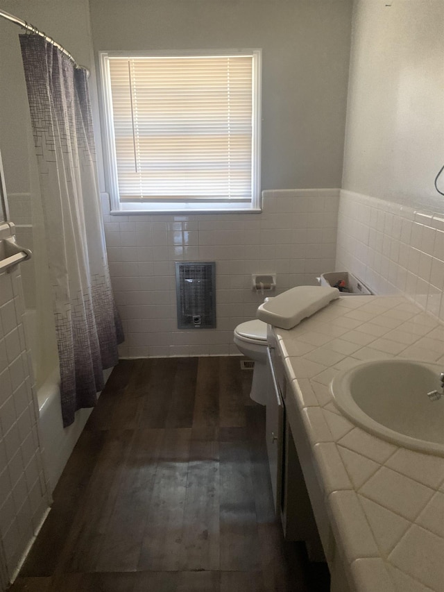 full bathroom with toilet, heating unit, wood-type flooring, shower / tub combo, and vanity