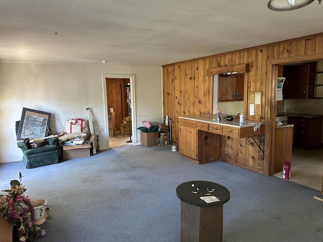 kitchen featuring wood walls, light colored carpet, and crown molding