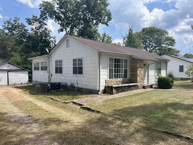 view of front facade featuring central AC unit, a garage, an outdoor structure, and a front yard