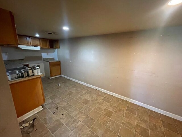  - kitchen featuring under cabinet range hood, recessed lighting, brown cabinets, and light countertops