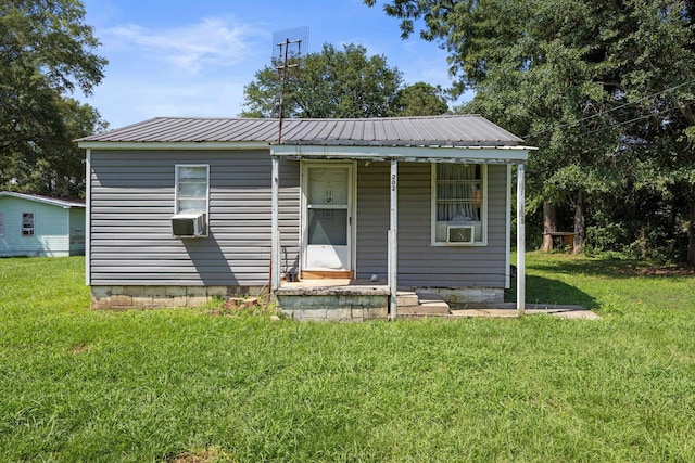 - view of front facade featuring a porch, a front lawn, metal roof, and cooling unit