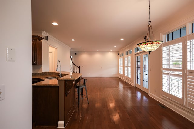 kitchen featuring hanging light fixtures, dark brown cabinetry, a breakfast bar, and a sink