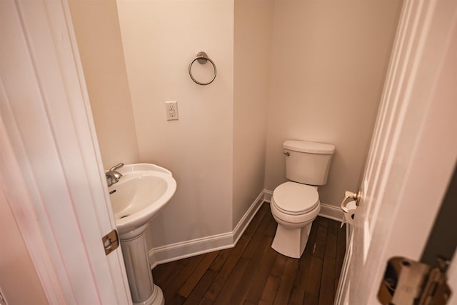 bathroom with toilet, a sink, baseboards, and wood finished floors