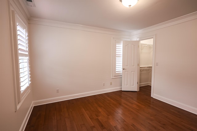 spare room featuring dark wood-style floors, visible vents, baseboards, and crown molding