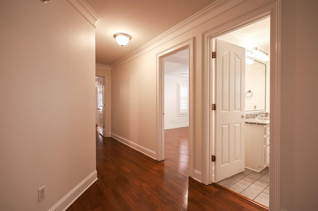 hallway with baseboards, wood finished floors, and crown molding