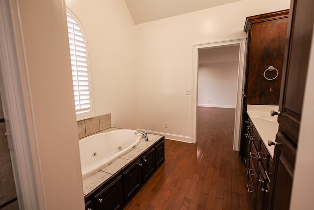 bathroom featuring a whirlpool tub, baseboards, wood finished floors, and vanity