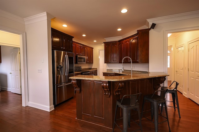 kitchen with a peninsula, dark wood-style flooring, ornamental molding, appliances with stainless steel finishes, and a kitchen bar