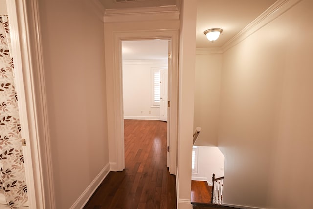 hallway with an upstairs landing, dark wood finished floors, crown molding, and baseboards