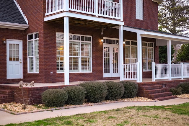 entrance to property featuring roof with shingles and brick siding