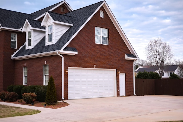 view of property exterior with a garage, brick siding, a shingled roof, fence, and concrete driveway