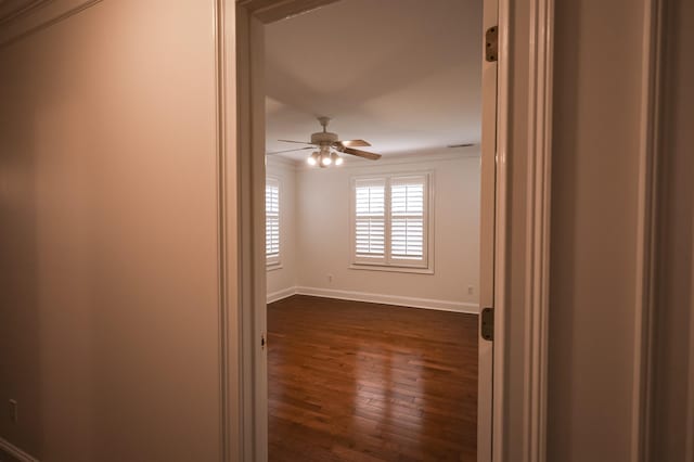 unfurnished room featuring dark wood-style flooring, ceiling fan, and baseboards