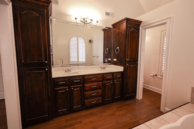 bathroom with double vanity, wood finished floors, a sink, and visible vents