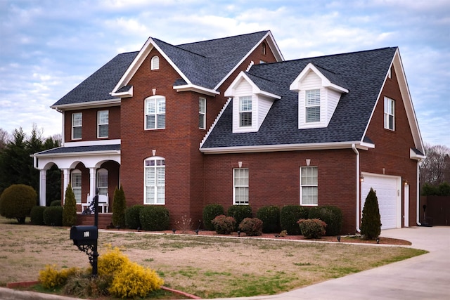 view of front of home with brick siding, a porch, a shingled roof, an attached garage, and driveway