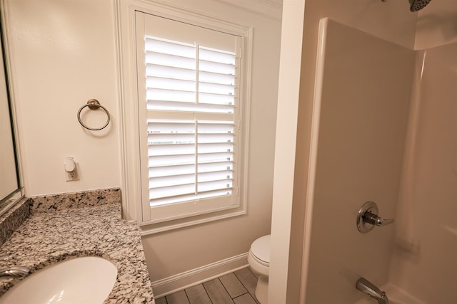 bathroom featuring toilet, wood finished floors, vanity, baseboards, and walk in shower