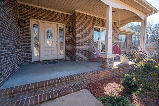 entrance to property with covered porch and brick siding