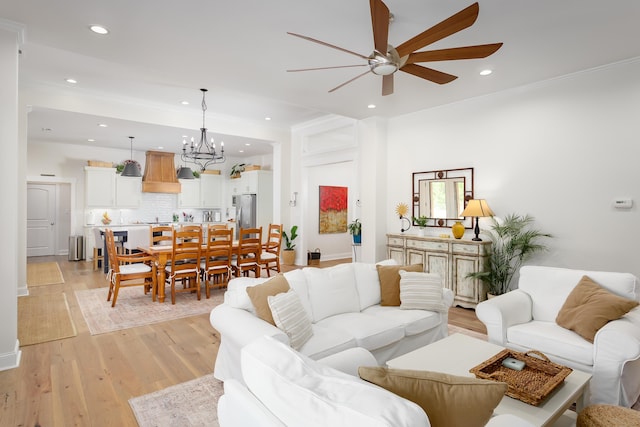 living room featuring ceiling fan with notable chandelier and light hardwood / wood-style floors