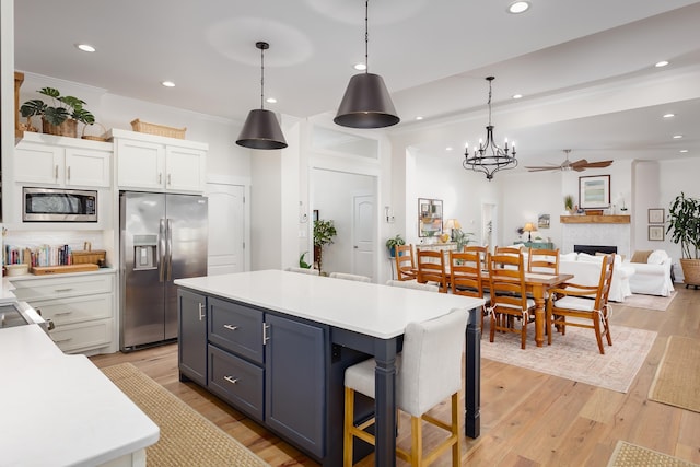 kitchen featuring crown molding, a breakfast bar, hanging light fixtures, stainless steel appliances, and white cabinets