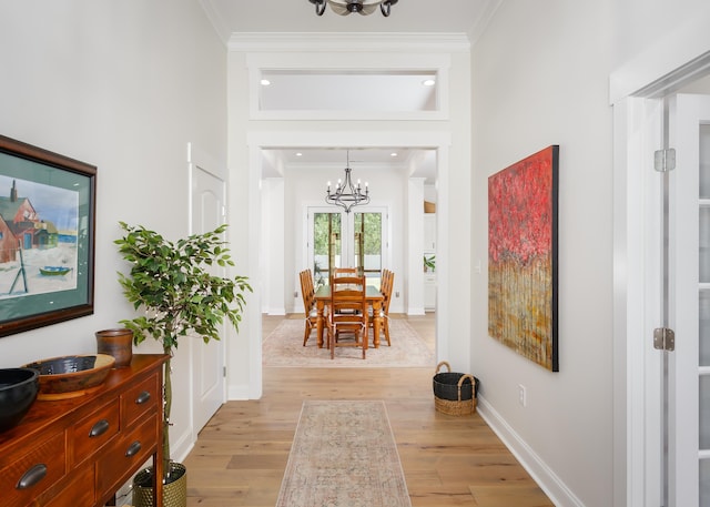 corridor featuring a notable chandelier, crown molding, and light hardwood / wood-style floors