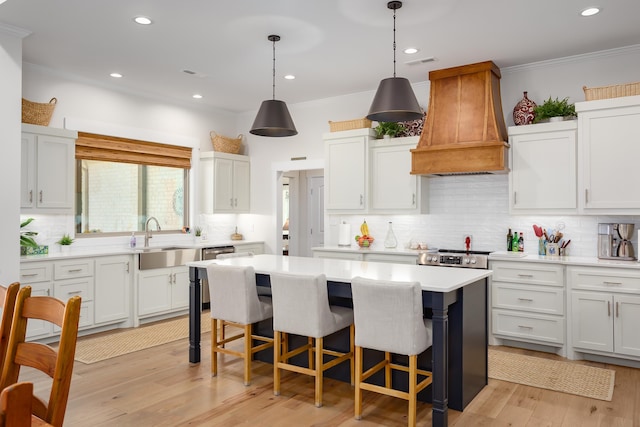 kitchen with white cabinetry, sink, custom exhaust hood, and a kitchen island