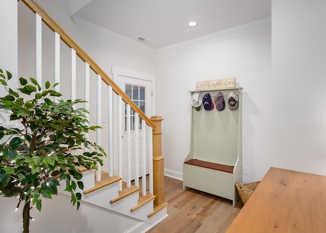 stairway with ornamental molding and hardwood / wood-style floors